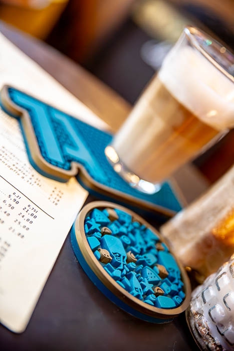 Ein Latte Macchiato auf einer stilvollen 1A-Barmatte mit eingearbeitetem Logo, begleitet von einer Getränkekarte.