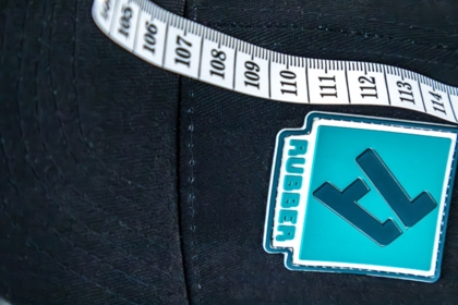 1a-rubber.de Logo-Patch auf schwarzer Cap mit Maßband – Aufnähservice