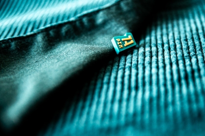 1A Rubber Pin mit blauem und goldenen Details auf dunkelblauem Stoff – Stilvoller Soft-PVC-Anstecker für Corporate Identity