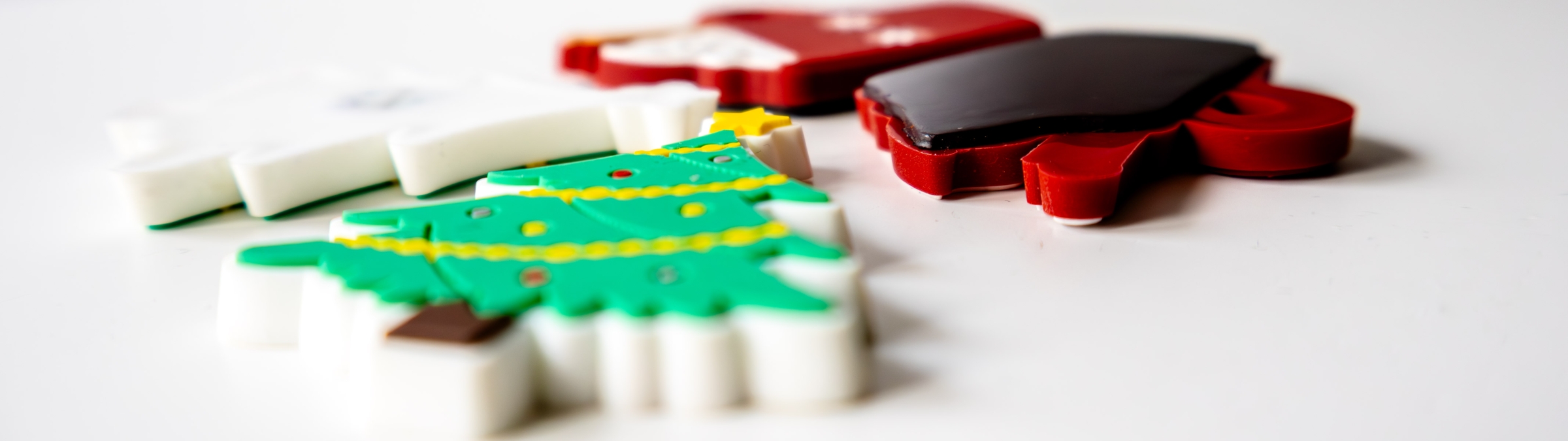 Mehrere weihnachtliche Gummi-Magnete in Form eines Tannenbaums und einer Tasse mit Heißgetränk