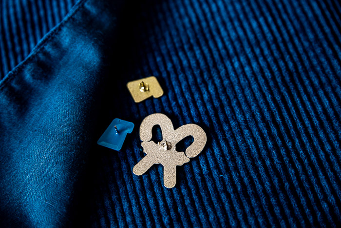 Rückseite von drei 1A Pins mit Nadel für verschiedene Metallverschlüsse auf blauem Stoff – zum sicheren Befestigen